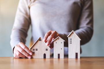 Closeup image of a woman holding wooden house models on the table