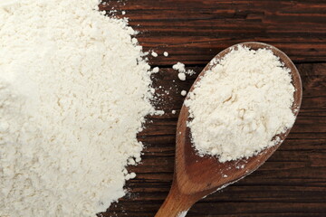 Pile of flour and wooden spoon with wheat flour on plank table. Directly Above.
