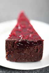 Cheesecake with chocolate crumb base topped with raspberry jelly