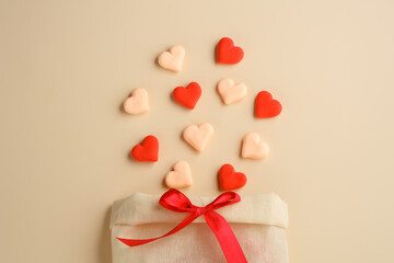 Bag with a bow of sweets-hearts and a ribbon on a beige background. Valentine's day holiday. greeting card