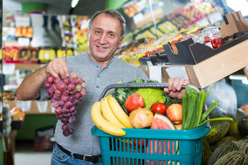 Ordinary man is demonstraiting basket with variety goods in the fruit store