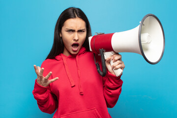young latin woman looking angry, annoyed and frustrated screaming wtf or what’s wrong with you