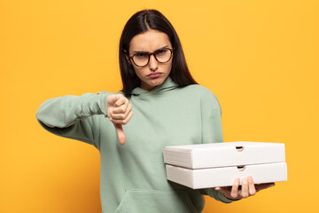 young latin woman feeling cross, angry, annoyed, disappointed or displeased, showing thumbs down...