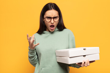 young latin woman looking angry, annoyed and frustrated screaming wtf or what’s wrong with you
