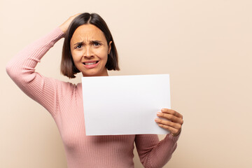 young latin woman feeling stressed, worried, anxious or scared, with hands on head, panicking at...
