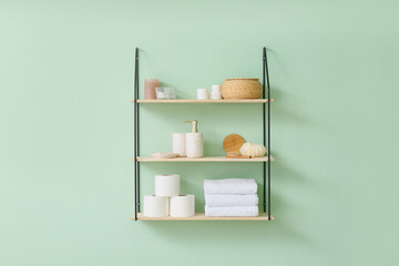 Shelf with bath accessories on color wall