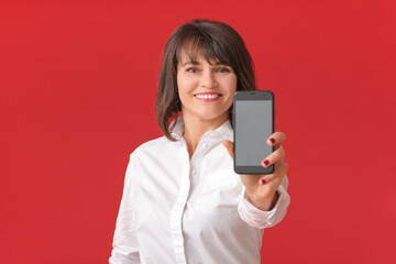 Naklejka premium Beautiful mature woman with mobile phone on color background