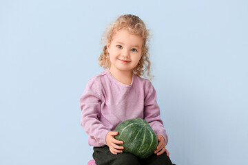 Fototapeta premium Cute little girl with pumpkin on color background