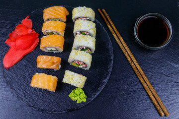 Set of sushi rolls on a black stone slate. Top view