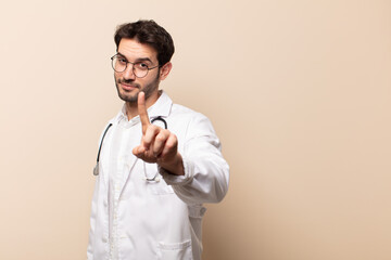 young handsome man smiling proudly and confidently making number one pose triumphantly, feeling...