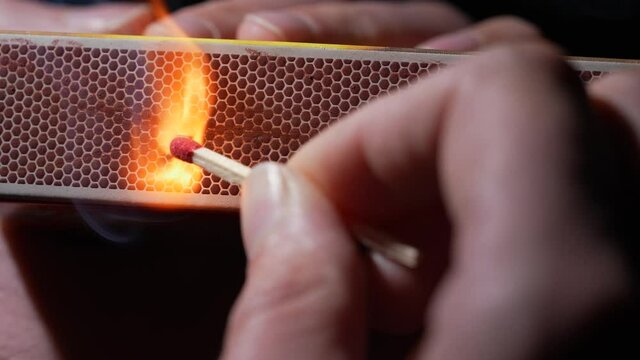 This close up, slow motion video shows an anonymous hand lighting a match.