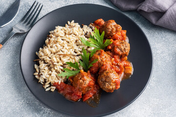 Beef meatballs and brown rice on a plate. Ready made portioned dish meat with garnish.