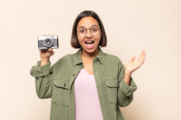 young latin woman feeling happy, excited, surprised or shocked, smiling and astonished at something...