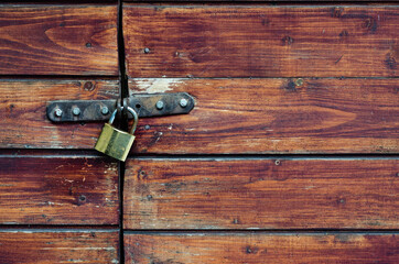 Closed padlock on a painted brown pine wooden door