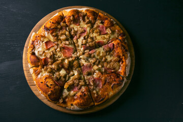 Pineapple and Ham Hawaiian Pizza on black rustic wood background. Top view of hot pizza. With copy space for text. Flat lay. flag