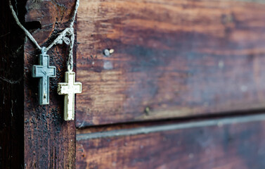 Two Christian crosses hanging near a wooden wall