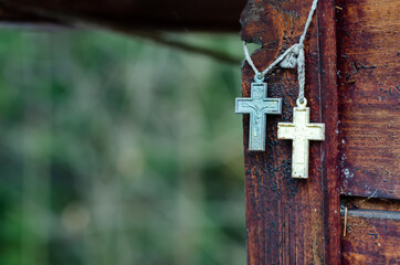 Two Christian crosses hanging near a wooden wall.
