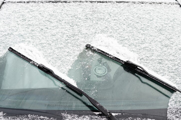 Car windows and wipers covered with snow in winter