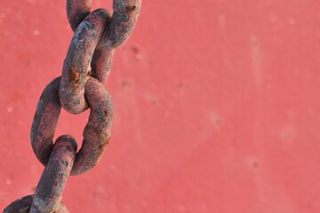 Weathered chain, rusty, with red painted background.  Off center.