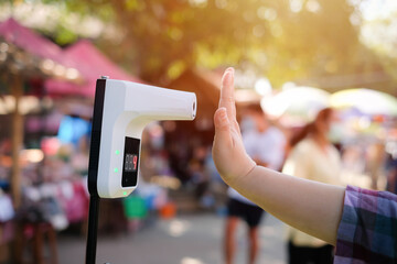 People using infrared contactless temperature assessment devices for measuring body temperatures COVID-19 flu screening at the entrance