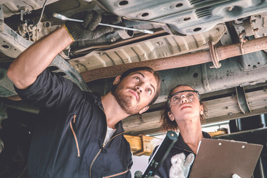 Man And Woman Auto Mechanic Working Team Checking Under Car For Auto Maintenance And Service In Garage