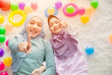 Fototapeta na wymiar Cute Muslim Arab mother and her girl child happy playing together with colorful balls fun and lovely