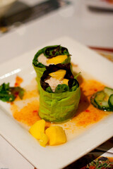 A serving of lettuce-wrapped sushi roll on a plate with pickles