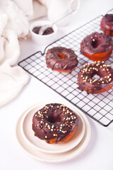 Doughnut on the baking rack and on the plate glazed with chocolate cream or icing. Breakfast concept.