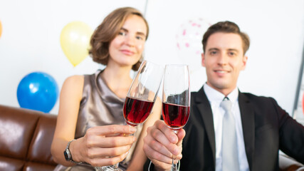 Caucasian couple friends smile and cheers glass of red wine beverage for celebration moment in seasonal such as Valentine’s Day, Happy Anniversary, Christmas party and New Year holiday together