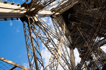 Architecture of Eiffel Tower. Closeup view of metal frames, beams, rivets against blue sky as...