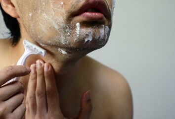 髭を剃る上半身裸の男性のクローズアップ