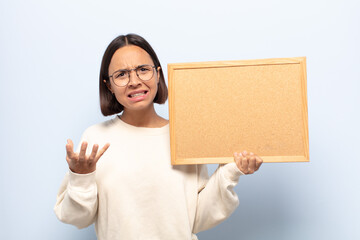 young latin woman looking angry, annoyed and frustrated screaming wtf or what’s wrong with you