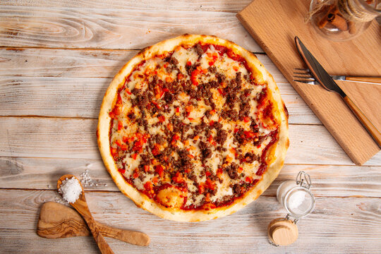 Top view on minced meat pizza on the rustic wooden background