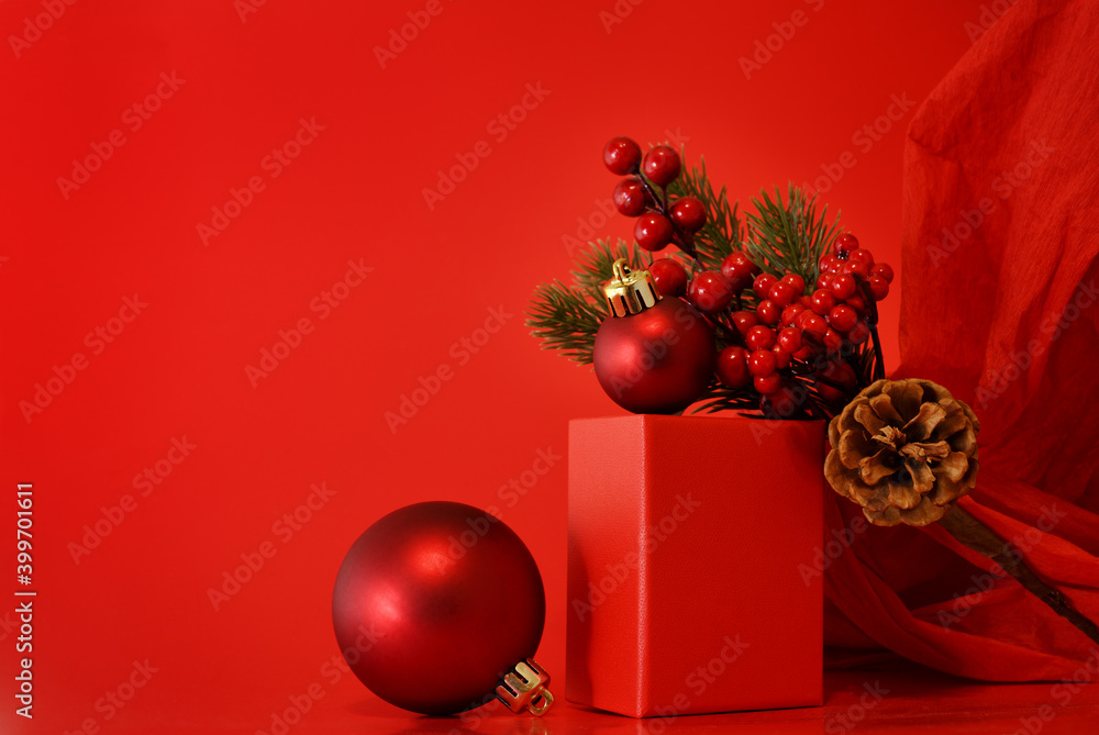 Wall mural red decorations and christmas tree branch on a podium on red background with crumpled paper