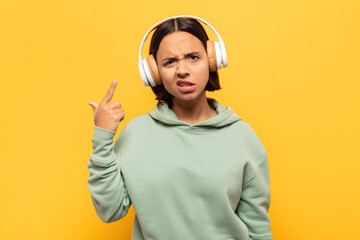 young latin woman feeling confused and puzzled, showing you are insane, crazy or out of your mind
