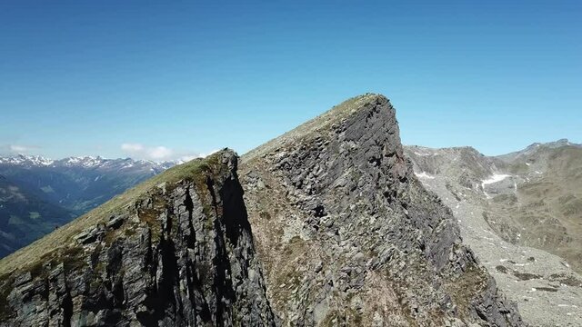 A panoramic drone capture of the mountains and a valley in the region of Bose Nase, Austrian Alps. There is Weissensee lake at the bottom of the valley. Idyllic and serene landscape. Small snow fields