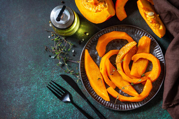 Pumpkin winter dessert. Baked pumpkin slices with honey and thyme on a stone countertop. Top view flat lay. Copy space.