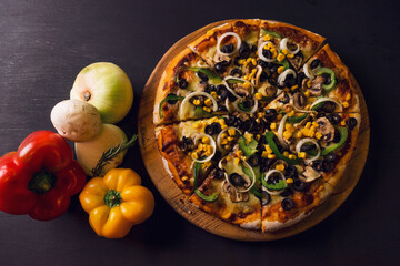 top view authentic Italian Pizza with black olives and vegetable rustic black wooden background. Top view of hot pizza.