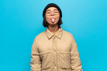 young latin woman with cheerful, carefree, rebellious attitude, joking and sticking tongue out,...