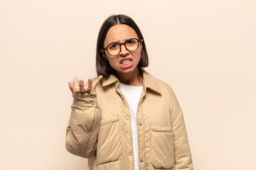 young latin woman looking angry, annoyed and frustrated screaming wtf or what’s wrong with you
