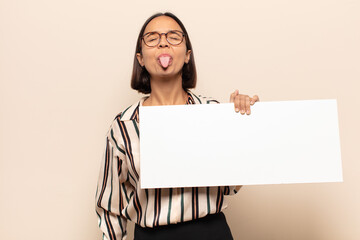 young latin woman with cheerful, carefree, rebellious attitude, joking and sticking tongue out,...
