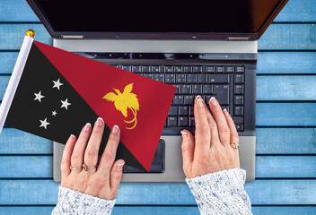 woman hands and flag of Papua New Guinea on computer, laptop keyboard 