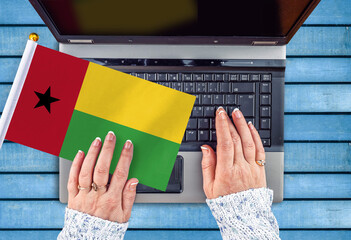 woman hands and flag of Guinea-Bissau on computer, laptop keyboard 