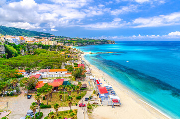 Tropea town cityscape with camping and green trees in park, colorful buildings on rock cliff, sandy...