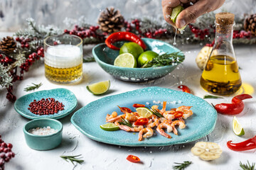 Prawns on plate. Shrimps, prawns with lime, rosemary, chili on a blue plate. Seafood. hand with lime splash juice
