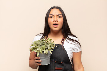 young latin woman looking very shocked or surprised, staring with open mouth saying wow