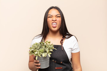 young latin woman feeling disgusted and irritated, sticking tongue out, disliking something nasty...