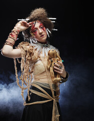 Young woman in zombie style holding a toy bunny in her hands. Bright make up and hairstyle. Party concept.