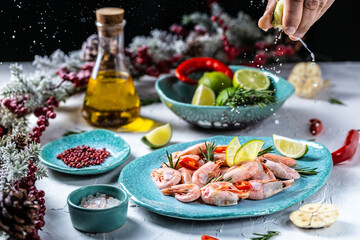 Fototapeta na wymiar Boiled shrimps or prawns with lime, rosemary, chili on a blue ceramic plate. Cook hand sprinkling lime juice splash. freeze motion