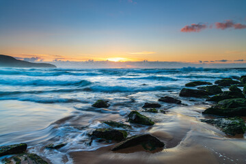 Sunrise seascape with light cloud, waves and rocks